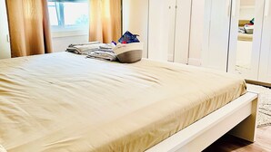 A bedroom with a bed, a wardrobe, and a window with curtains. - Entire Home with Three Bedroom at the heart of Vancouver (Vancouver)