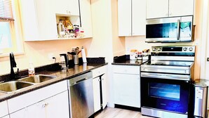 A modern kitchen with white cabinets, a dishwasher, a microwave, and an oven. - Entire Home with Three Bedroom at the heart of Vancouver (Vancouver)