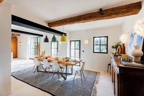 Ein moderner Essbereich mit einem Holztisch, weißen Stühlen und Pendelleuchten.