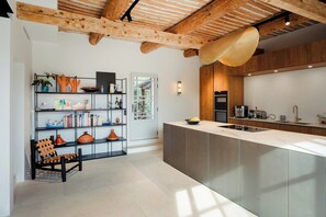Eine moderne Küche mit einer großen Kochinsel, Holzbalkendecke und einer eingebauten Bücherwand.