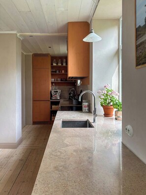 Eine Küche mit einer Arbeitsplatte aus Granit, einem Spülbecken, Holzschränken und einer Pendelleuchte.