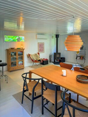 Ett rymligt rum med ett matbord och stolar i trä, en öppen spis och ett fönster med utsikt över grönområden.
