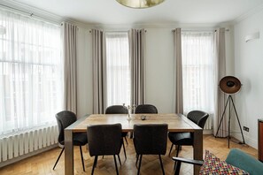 A dining room with a wooden table, six chairs, a floor lamp, and a radiator. - Modern 3BR Flat in Chelsea (London)