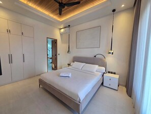Ein modernes Schlafzimmer mit Bett, Nachttischen, einem Kleiderschrank und einem Deckenventilator.