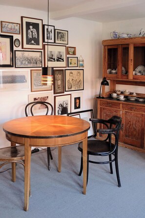 Ein Essbereich mit einem Holztisch und Stühlen, einem Schrank mit Geschirr und Bildern in Rahmen an der Wand.