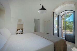 A bedroom with a bed, a hanging light, a wardrobe, and a door leading to an outdoor area. - Trullo with salt pool and sea view near Ostuni (Ostuni)