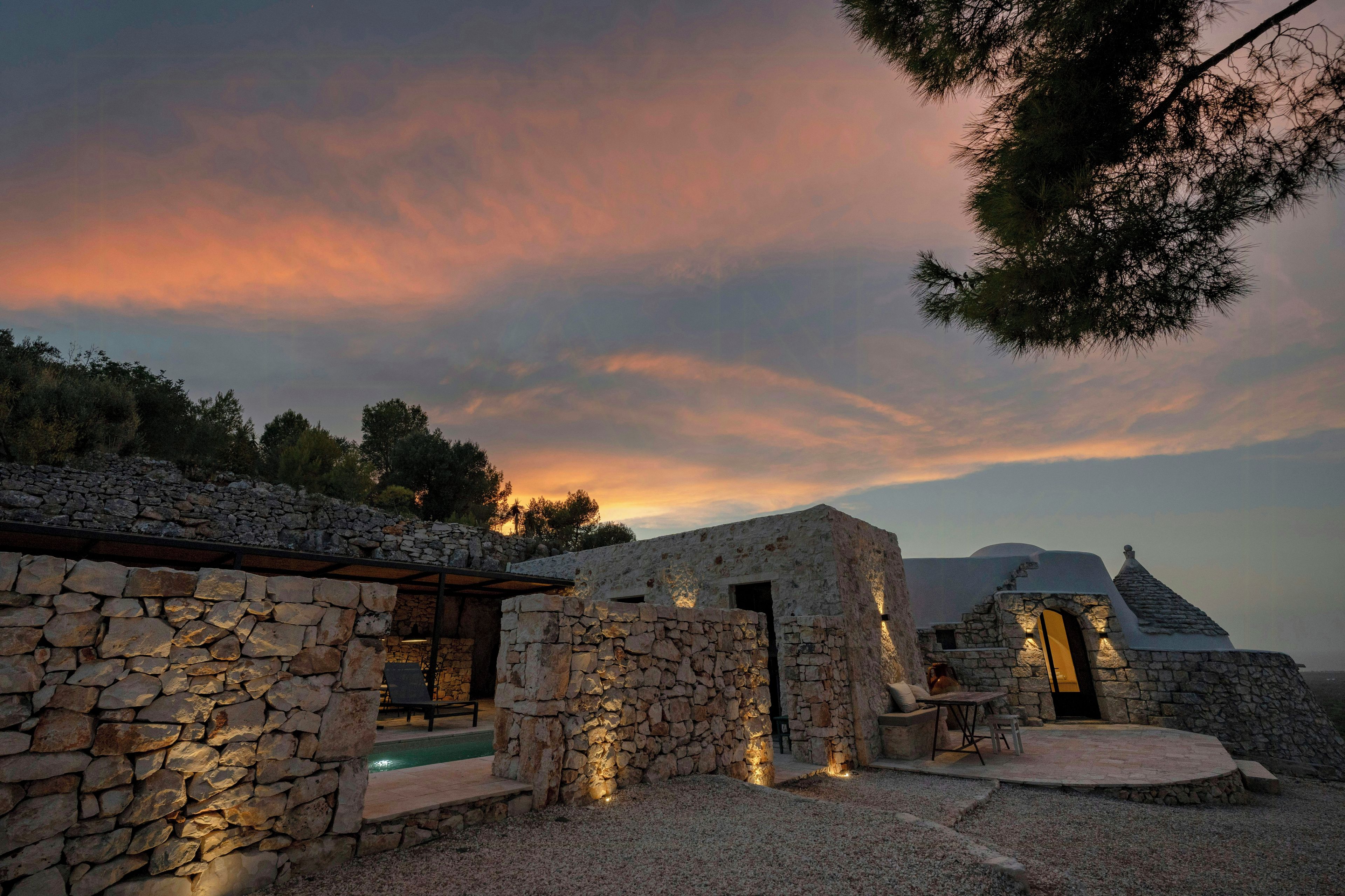 A stone building with a pool and outdoor seating area.