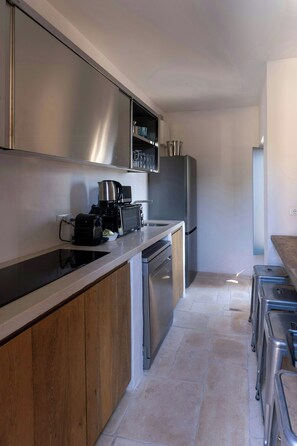 Eine moderne Küche mit Edelstahlgeräten, Holzschränken und Fliesenboden.