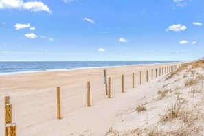 A sandy beach with wooden posts and a clear sky. - Dune Rose | Vagabond Ocean Block Surf House (Ocean City)
