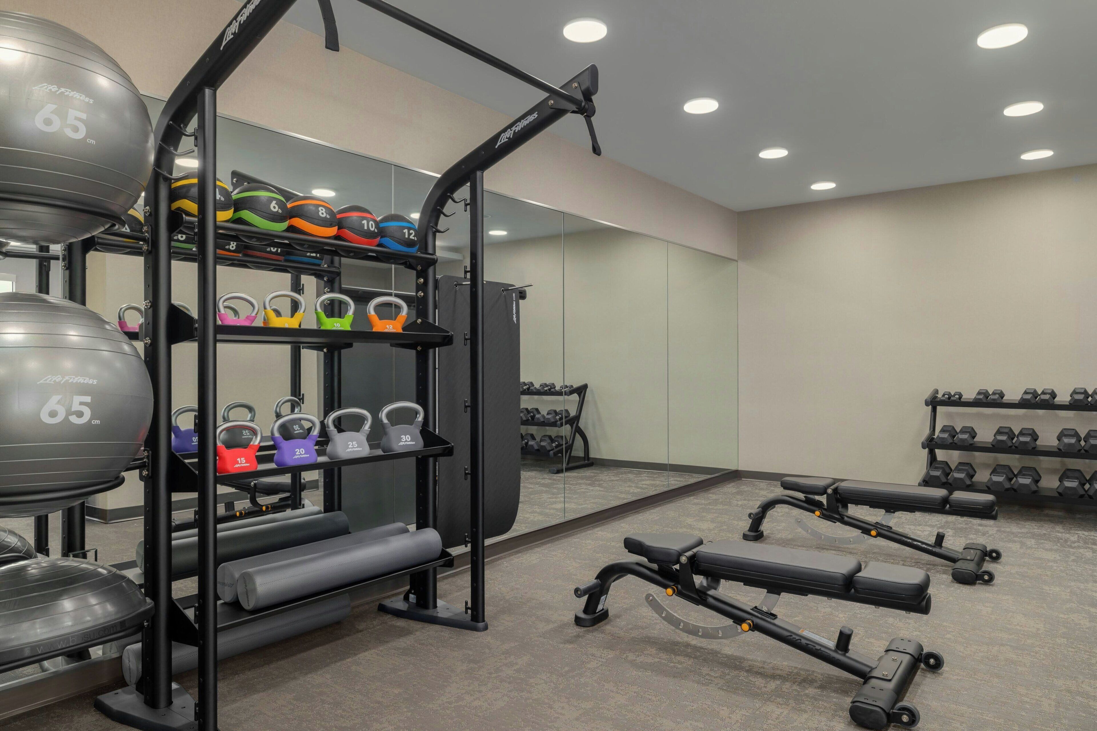 A gym with weightlifting equipment, including kettlebells, dumbbells, and a bench.
