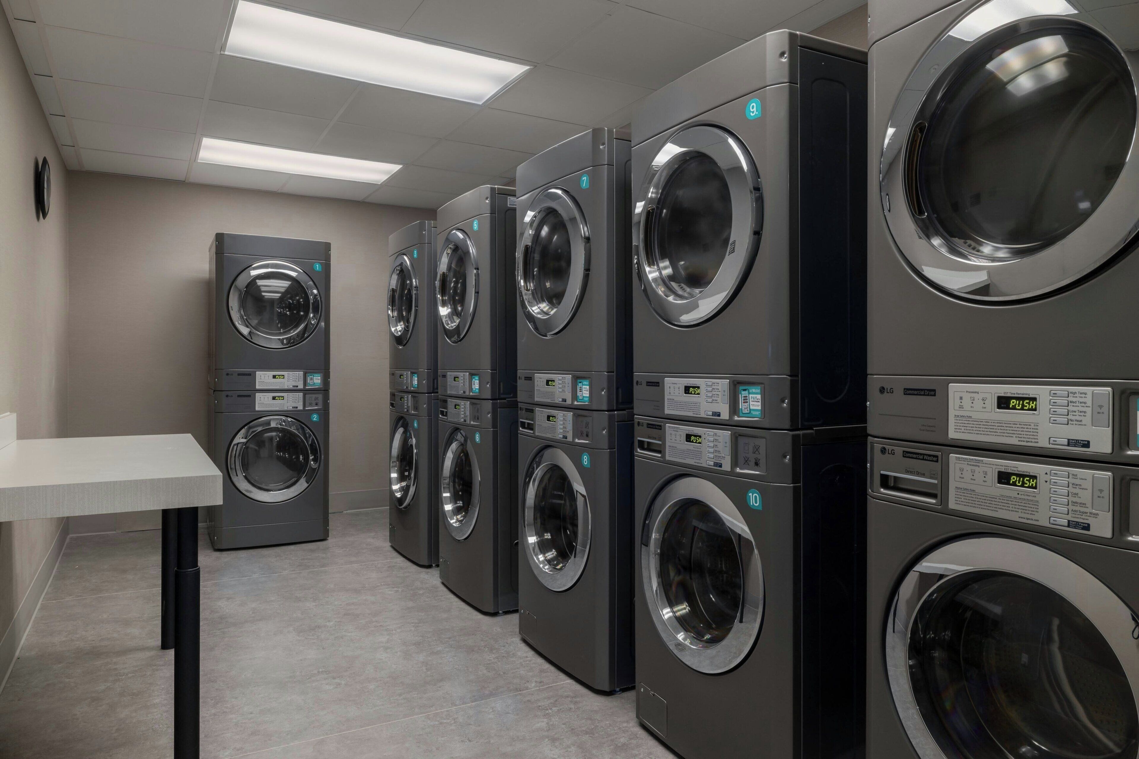 A row of commercial washers with control panels, numbered for identification, in a clean, well-lit room with a tiled floor.