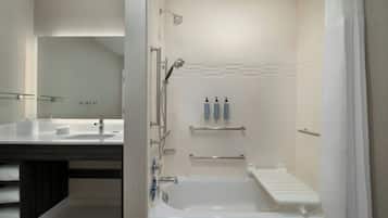 A modern bathroom with a bathtub, a shower, a vanity with a mirror, and a towel rack.
