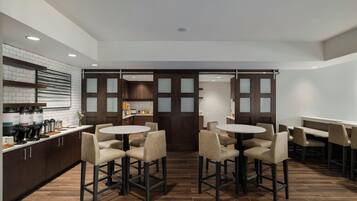 A modern kitchen with a central island, bar stools, and a dining area with tables and chairs.