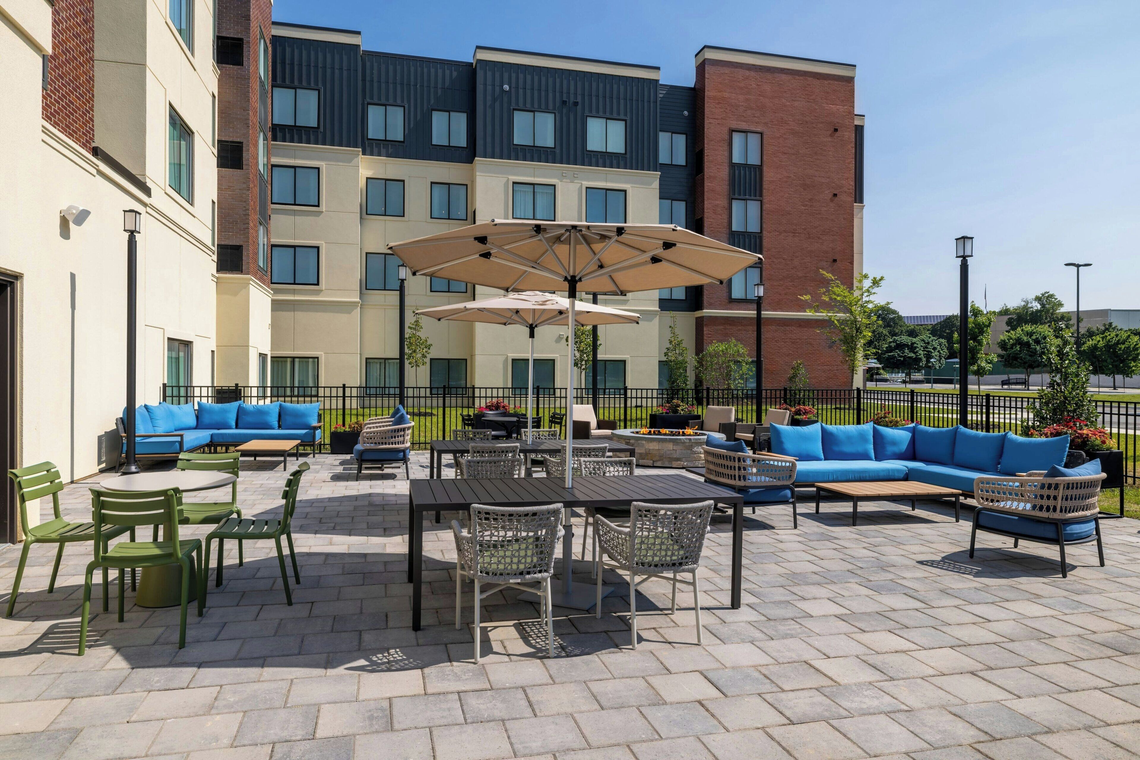 An outdoor patio area with seating arrangements, tables, and umbrellas.