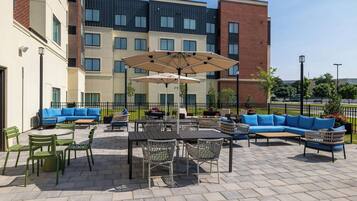 An outdoor patio area with seating arrangements, tables, and umbrellas.