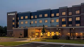 A multi-story hotel with a brick facade, multiple windows, and a parking lot.