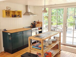Eine Küche mit Holzausziehtisch, einem Herd und einem Essbereich mit Tisch und Stühlen.