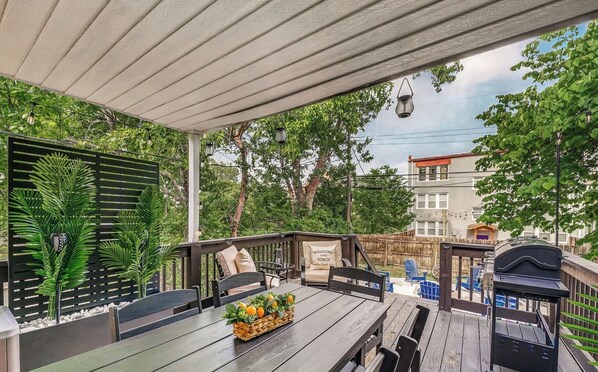 Eine Terrasse im Freien mit einem Holztisch, Stühlen und einem Grill.