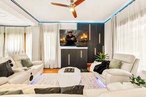 Ein modernes Wohnzimmer mit Flachbildfernseher, zwei Sofas, einem Couchtisch und einem Deckenventilator.