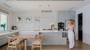 Eine moderne Küche mit einer zentralen Kochinsel, einem Essbereich mit Holzkästen und einem großen Fenster.
