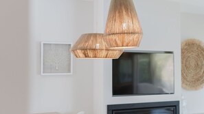 Ein modernes Interieur mit einer hängenden Leuchte, einem gerahmten Bild und einem an der Wand befestigten Flachbildfernseher.