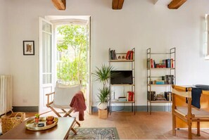Ein gemütliches Wohnzimmer mit Kamin, Bücherregal, Essbereich mit Tisch und Stühlen sowie Blick ins Grüne.