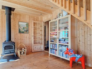 Ein Holzinnenraum mit Kamin, Bücherregal und einer farbenfrohen Skulptur eines Pferdes.