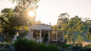 Uma casa moderna com varanda coberta, rodeada por vegetação exuberante e árvores.
