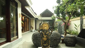 Eine Statue einer Elefantengottheit in einem Innenhof mit großen dekorativen Kugeln und einem Blumentopf.