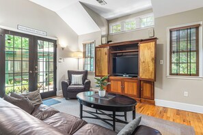 Ein Wohnzimmer mit einer Ledersofa, einem Couchtisch, einem Fernseher und Holzschränken.