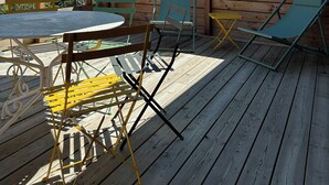 A wooden deck with a round table and chairs, a green umbrella, and a view of snow-capped mountains. - Renovated little house with High Alps view (Baratier)