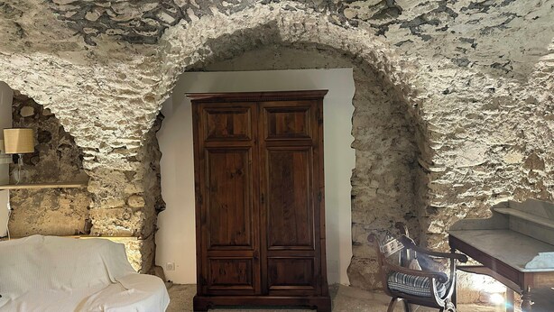 A room with a stone wall, a wooden wardrobe, a white sofa, and a rocking chair. - Renovated little house with High Alps view (Baratier)