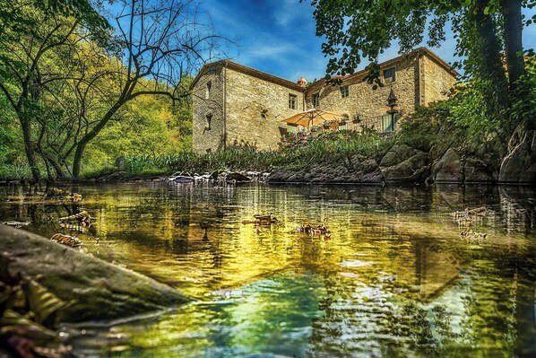 Ein Steinhaus mit Innenhof und Teich mit Schwänen.
