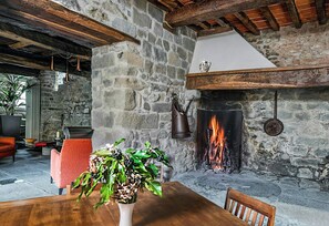 Ein Zimmer mit Stehwänden, einem Kamin, einem Holztisch und einem Blumentopf.
