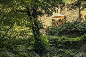 Ein Steingebäude mit einem Garten, einem Tisch mit Sonnenschirm und einer Laterne.