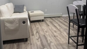 A modern living room with a sofa, ottoman, and a dining area with chairs. - Fabulous 2-bedroom house in Baldwin perfect for your getaway (Baldwin)