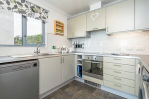 Eine moderne Küche mit Spülmaschine, Backofen und einer herzförmigen Dekoration an der Wand.