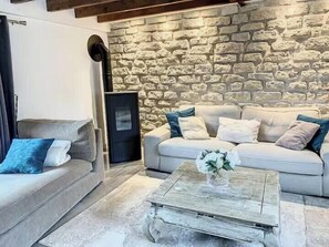 A living room with a stone wall, a sofa, a coffee table, and a fireplace. - Picardy house near Compiègne and Pierrefonds (Jaux)