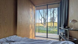 A bedroom with a bed, a desk, and a view of the outdoors. - Tiny house overlooking nature (Vordingborg)