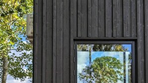 A wooden structure with a window reflecting a tree and sky. - Tiny house overlooking nature (Vordingborg)