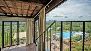 A balcony with a view of a swimming pool and surrounding greenery. - Charming apartment on a vineyard near Lucca (Segromigno in Monte)