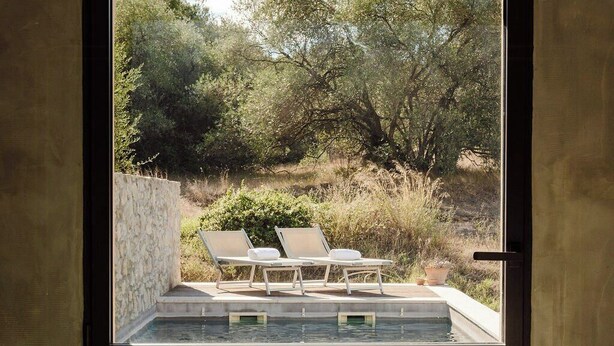A spa room with a large window overlooking a pool area with lounge chairs.