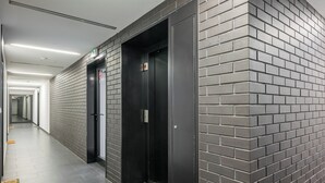 Un pasillo con dos ascensores, suelo de baldosas y pared de ladrillo.