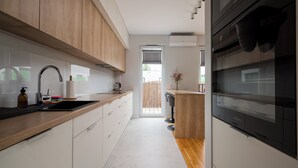 Una cocina moderna con encimera de madera, electrodomésticos de acero inoxidable y vistas al exterior.