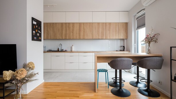 Una cocina moderna con armarios de madera, una isla central y taburetes de bar.