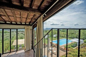 Ein Balkon mit Blick auf einen Pool und umliegendes Grün.