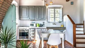 A kitchen with grey cabinets, a white countertop, a dining table with chairs, and a wooden staircase. - Vineyard with private pool near Lucca (Segromigno in Monte)