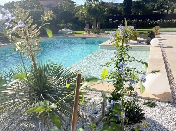 A swimming pool with clear water, surrounded by gravel and plants. - Designer villa near the Gulf of Saint-Tropez (Grimaud)