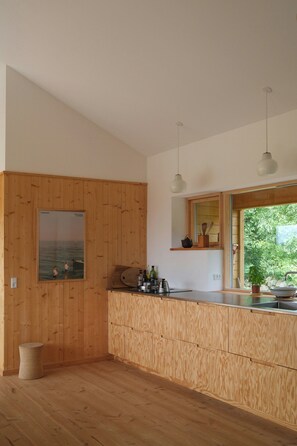 Eine moderne Küche mit Holzausstattung, einem Einbauofen und einem Fenster mit Blick auf Grünflächen.