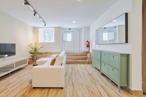 A modern living room with a sofa, TV, and a green cabinet. - Setúbal Heritage House (Setúbal)